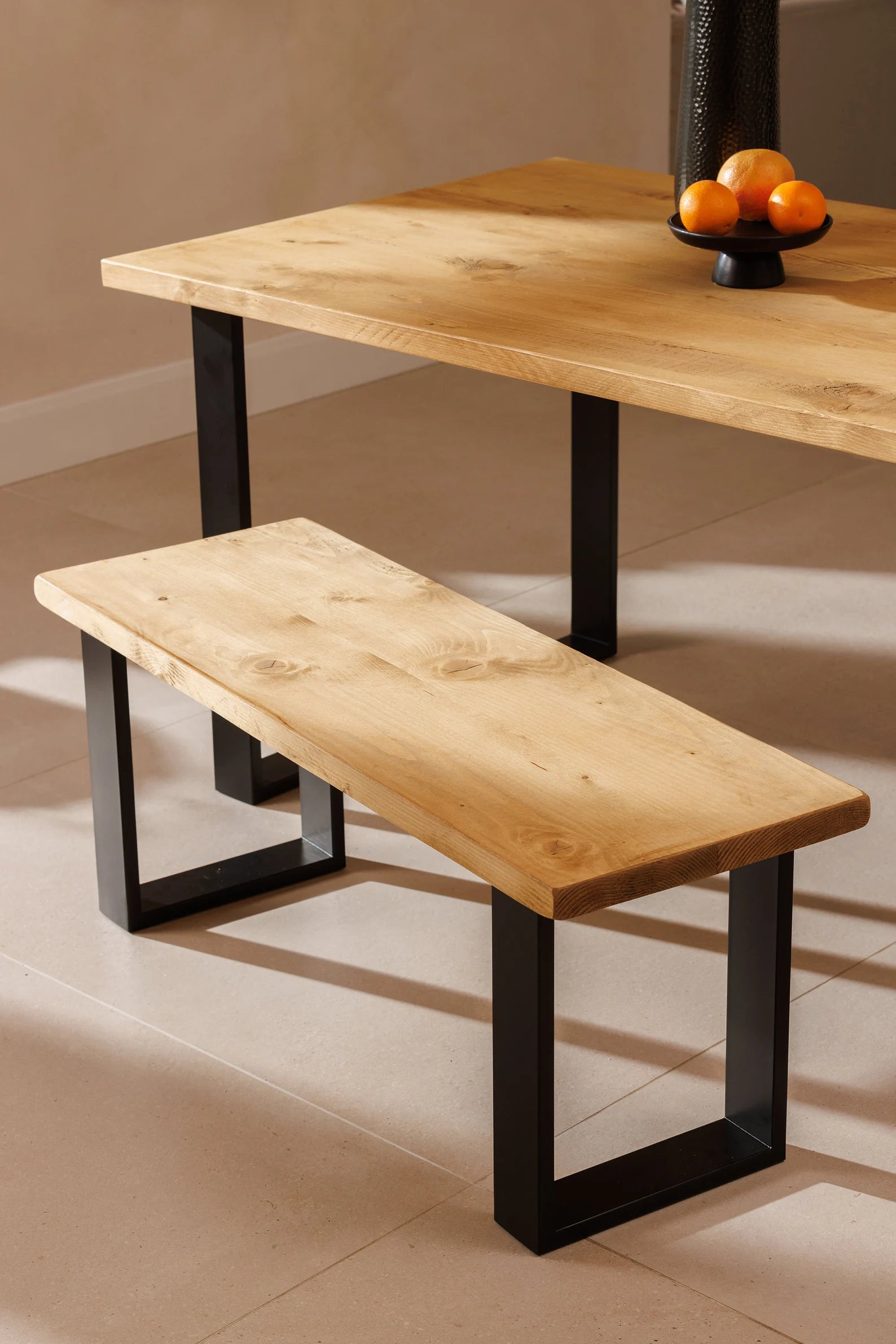 Wooden table and bench with black metal legs on a beige floor.